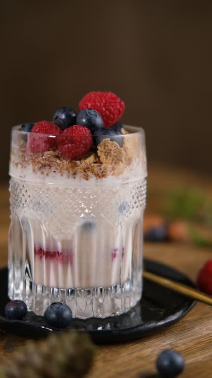 Granola with yogurt and berries for healthy breakfast on a wooden table. Dark style photography.