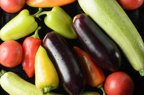 istock Bell peppers, tomatoes, zucchini, vegetables spread out on a black baking sheet. 1325129057