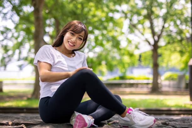 Portrait of young female athlete relaxing in public park Japanese young female athlete exercising in public park. Stretching, jogging, etc. olive green shirt stock pictures, royalty-free photos & images