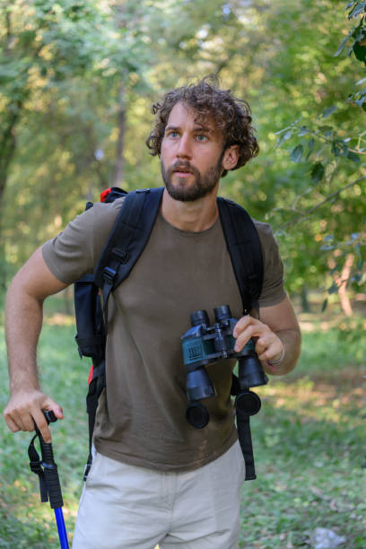 istock Young Man is Hiking in Forest in Nature and Using Binoculars. 1325132358