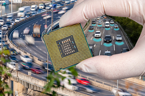 The computer circuit board and fast-moving cars. A hand holding a CPU chipset.
