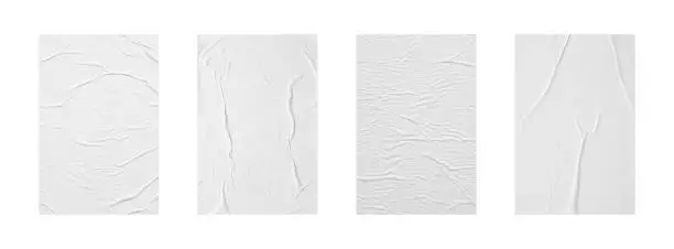 Photo of white crumpled and creased glued paper poster set isolated on white background