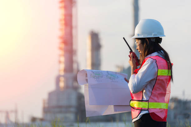 istock Engineers woman holding radio, blueprint and report schedule for workers security control at power plant energy industry. Engineer Concept 1325148766