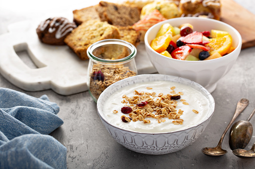 Breakfast table with granola, yogurt and fruit and pastries