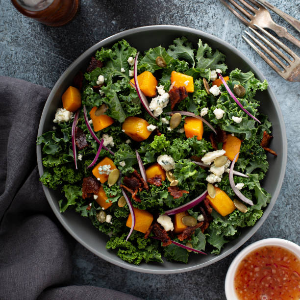 Fall salad with kale and butternut squash Fall salad with kale and butternut squash, blue cheese and hot bacon dressing hot mix plant stock pictures, royalty-free photos & images
