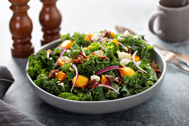 Fall salad with kale and butternut squash Fall salad with kale and butternut squash, blue cheese and hot bacon dressing Kale Salad with Butternut Squash, Pomegranate, and Pumpkin Seeds stock pictures, royalty-free photos & images