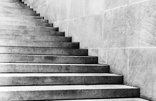 Diagonal view of outdoor gray stone staircase along stone wall Diagonal view of outdoor gray stone staircase along a stone wall. Gray-scale image. outdoor staircase stock pictures, royalty-free photos & images