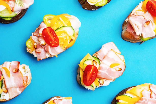 istock Trendy open sandwiches with cream cheese, quail eggs, tomatoes, bacon and vegetables. Modern, summer still life of healthy snacks.  Flat lay in minimalism style. Smorrebrod with various stuffing. 1325156769