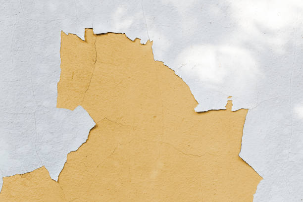 istock Cracked white paint on concrete wall background and see old yellow paint 1325157604