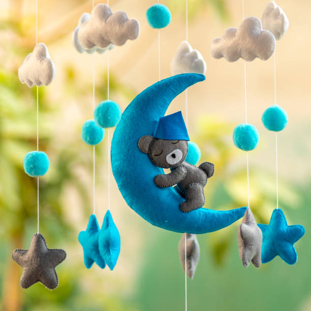 baby crib hangings, felt cot mobile made with plush clouds, moon, and stars. space-themed handmade hanging close up against soft blurred background. - using mobile imagens e fotografias de stock