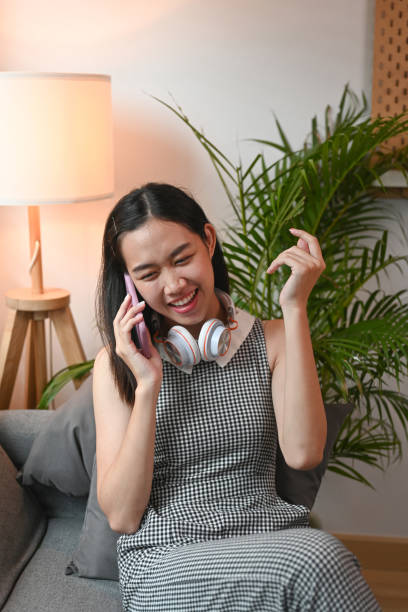 istock Happy young woman talking on mobile phone with her friends while sitting on sofa. 1325159046