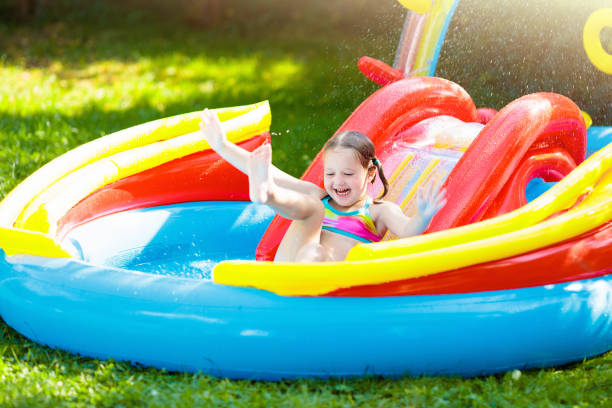 istock Child in garden swimming pool with slide 1325161921