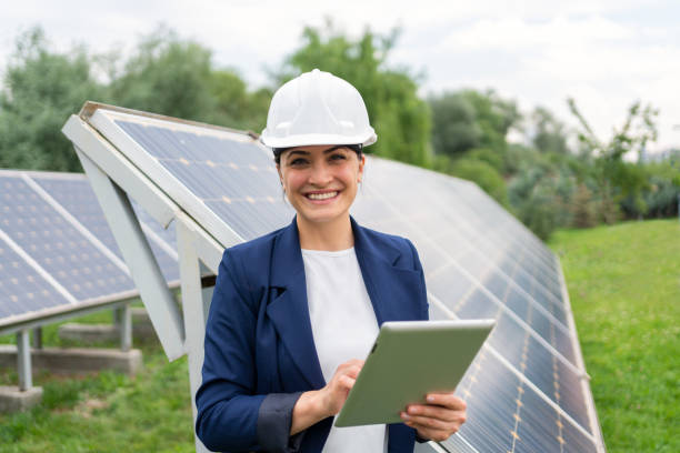 女性マネージャーエンジニアのイン安全ヘルメットは、ソーラーステーションでのソーラーパネルシステムの操作をタブレットでチェック - solar panel engineer solar power station solar energy ストックフォトと画像
