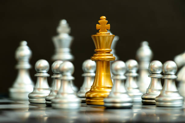 istock Gold king in chess game surrond with the another silver team on black background (Concept for company strategy, business crisis or decision) 1325169041