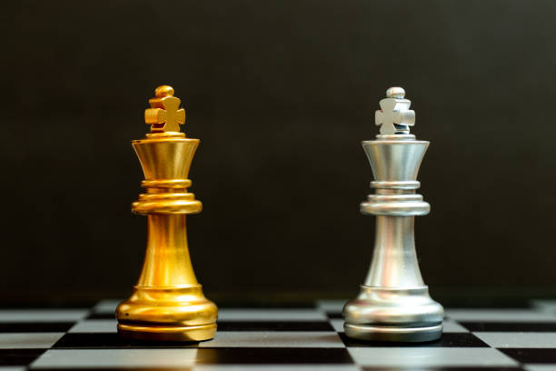 istock Gold king in chess game face with the another silver king on black background (Concept for company strategy, business victory or decision) 1325169077