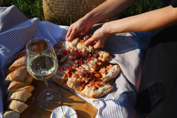 close-up shot: hands grab a slice of pizza at a picnic by the lake