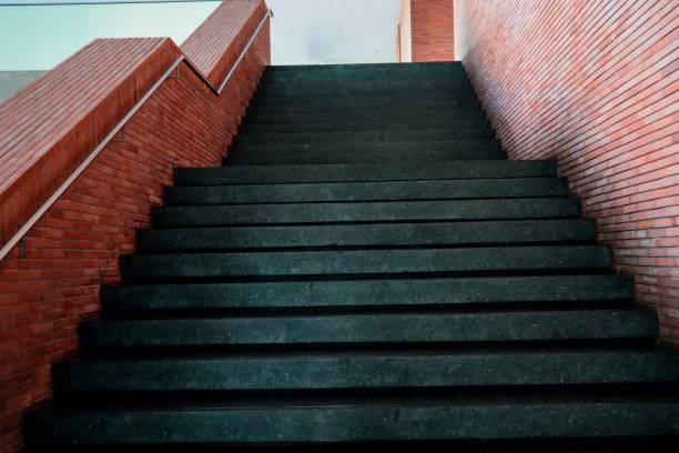Empty black stone stairway near old brick wall, abstract architectural background.