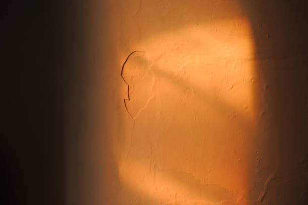 The orange colored texture of the wall with dark shadows in the afternoon