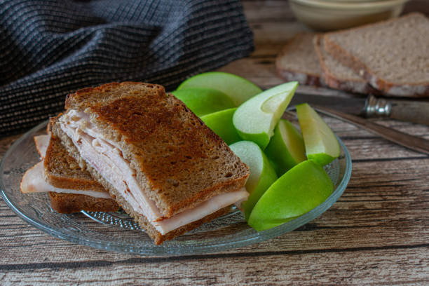Ham Sandwich with rye bread fresh and homemade toasted sandwich with rye bread and thin sliced chicken breast served with green apples on a glass plate on rustic table green apple slice overhead stock pictures, royalty-free photos & images