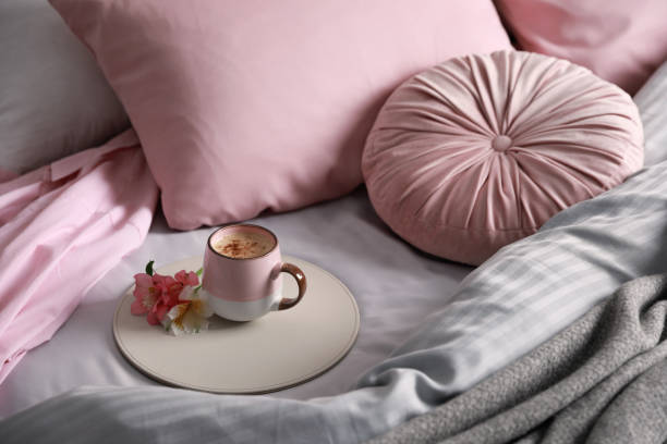 istock Aromatic coffee and beautiful flowers on bed with fresh linens 1325179851