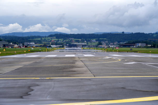 pista bagnata vuota per emmen air base dell'aeronautica svizzera con drammatico sfondo del cielo in una giornata estiva. - runway airport sky wet foto e immagini stock