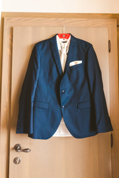 istock Groom suit and white tie hanging on a door 1325183477