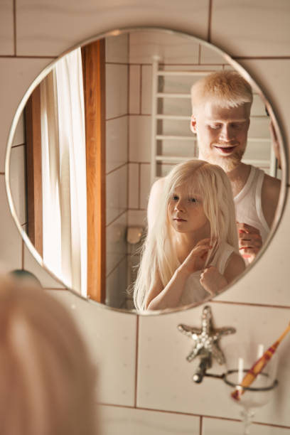 istock Man doing hairstyle for his little daughter at the bathroom while smiling 1325185193