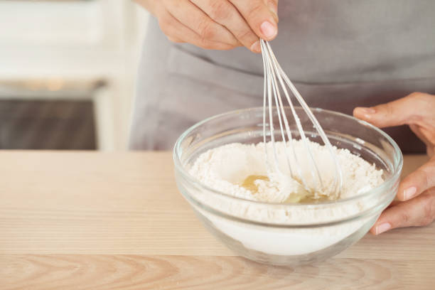 istock Woman Hand Mixed Batter on Clear Bowl with Baloon Whisk Step by Step Baking Preparation in the Kitchen 1325185903