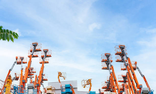 Articulated boom lift. Aerial platform lift. Telescopic boom lift against blue sky. Mobile crane parked at parking area for rent. Hydraulic boom lift at parking lot of crane dealership sale office. elevador de pluma articulada. elevador de plataforma aérea. elevación telescópica de la pluma contra el cielo azul. grúa móvil aparcado en zona de aparcamiento en alquiler. elevador de pluma hidráulica en el estacionamiento de la oficina de venta del