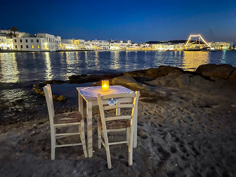 Table and chairs at night, Mykonos town (Chora), Mykonos island, Cyclades, Greece.