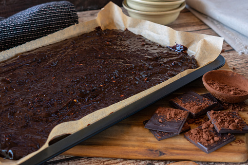 fresh prepared brownie batter on baking tray on rustic wooden table background. Front view