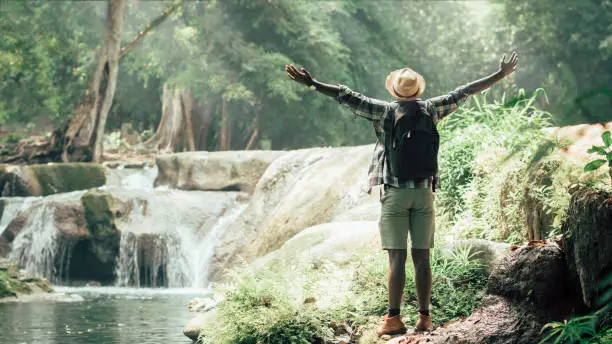 Photo of African man traveler standing on the water fall  with smile and happy.16:9 style