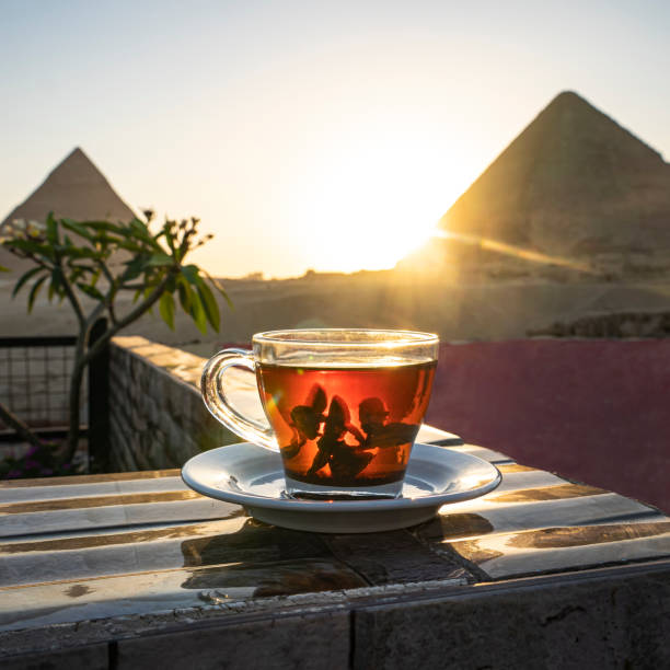 tomar té de menta en un café mientras contempla las impresionantes tres pirámides de giza. taza de vidrio transparente con té negro y menta en el fondo de las pirámides egipcias. - pyramid of chephren fotografías e imágenes de stock