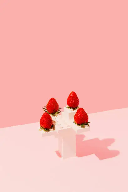 Photo of Ripe red strawberries on a white plastic toy bricks construction against pink background. Minimal summer fruit aesthetic still life. Surreal fresh food sculpture concept.