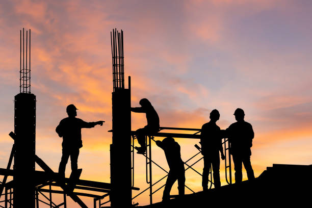 istock Silhouette of Engineer and worker on building site, construction site at sunset in the evening time. 1325192151