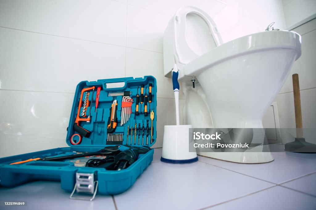 Close up photo of ceramic bowl toilet in domestic bathroom with a box of tools Toilet Stock Photo