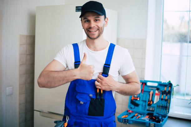 jovem reparador profissional em uniforme de trabalhador e boné com caixa de ferramentas moderna com equipamento após reparo de geladeira na cozinha - coveralls professional occupation manual worker service occupation - fotografias e filmes do acervo