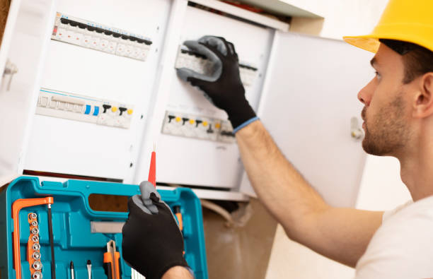istock Confident young electrician in helmet and gloves is checking with an electrical panel with fuses 1325195091