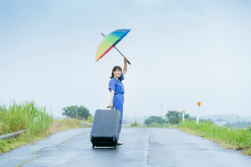 Asian young woman with suitcase and colorful umbrella