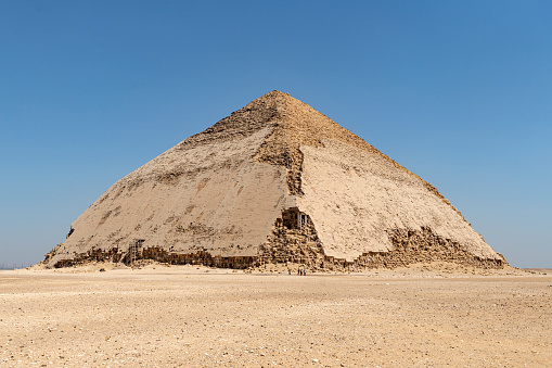 View of Pyramid of Snefru, Bent Pyramid on a blue sky background, at Dahshur, Egypt. The southern pyramid in Dahshur is called cut or diamond-shaped because of its irregular shape.