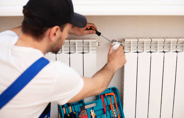 istock Professional young repairman in special uniform with tools is installing radiators and thermostat in domestic room 1325195803