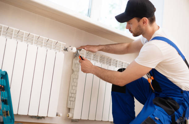 istock Professional young repairman in special uniform with tools is installing radiators and thermostat in domestic room 1325195820