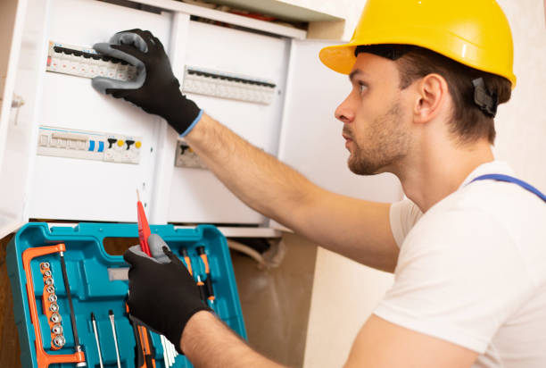 istock Confident young electrician in helmet and gloves is checking with an electrical panel with fuses 1325195894