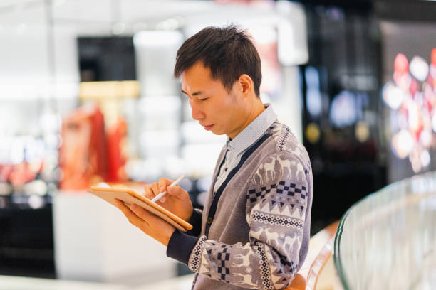 istock Asian man using tablet in shopping mall 1325197604