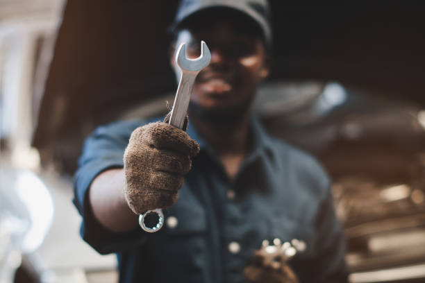 African maintenance male holding screw driver for checking car,service via insurance system at automobile repair and check up center stock photo