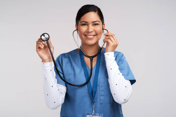 portrait of a young doctor using a stethoscope against a white background - ouvindo batidas do coração imagens e fotografias de stock