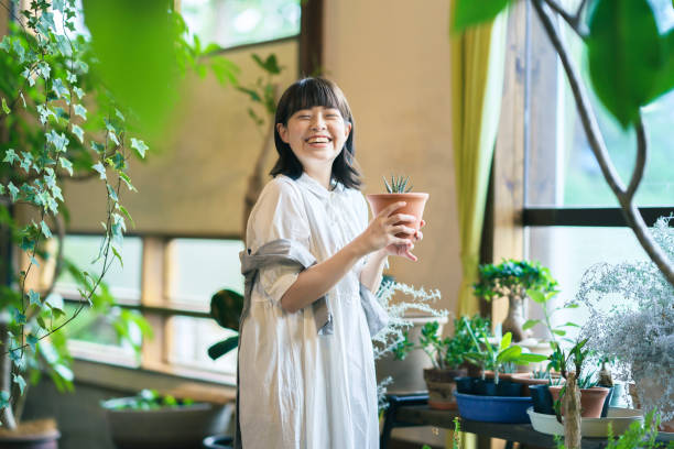 葉の植物を見ている若い女性 - japanese culture japan japanese ethnicity asian and indian ethnicities ストックフォトと画像