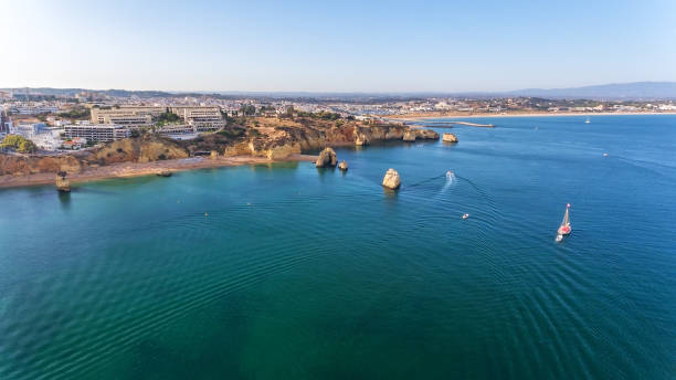 Dona Ana Beach in Lagos, Algarve - Portugal. Portuguese southern golden cliffs. Camilo and pinhao beach. Aerial view with city in background. Dona Ana Beach in Lagos, Algarve - Portugal. Portuguese southern golden coast cliffs. Camilo and pinhao beach. Aerial view with city in the background. High quality photo alvor stock pictures, royalty-free photos & images
