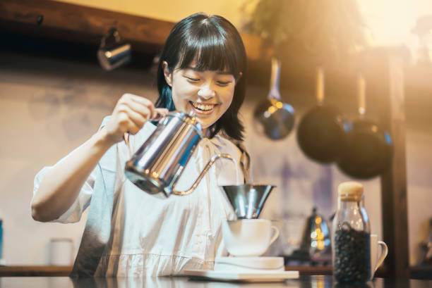 une jeune femme brassant du café avec un goutte-à-goutte à la main - le monde des cafés photos et images de collection