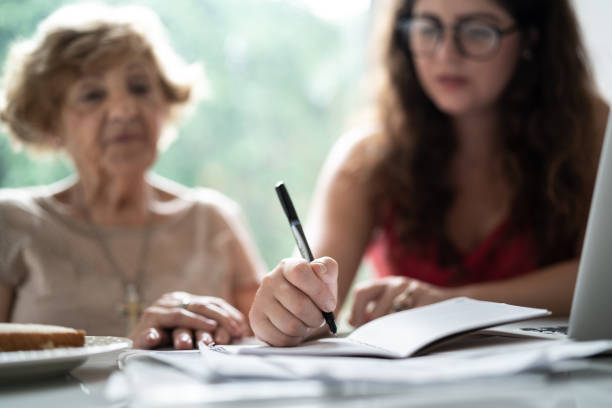 granddaughter helping granddaughter with doing home finances - finance senior adult financial advisor meeting imagens e fotografias de stock